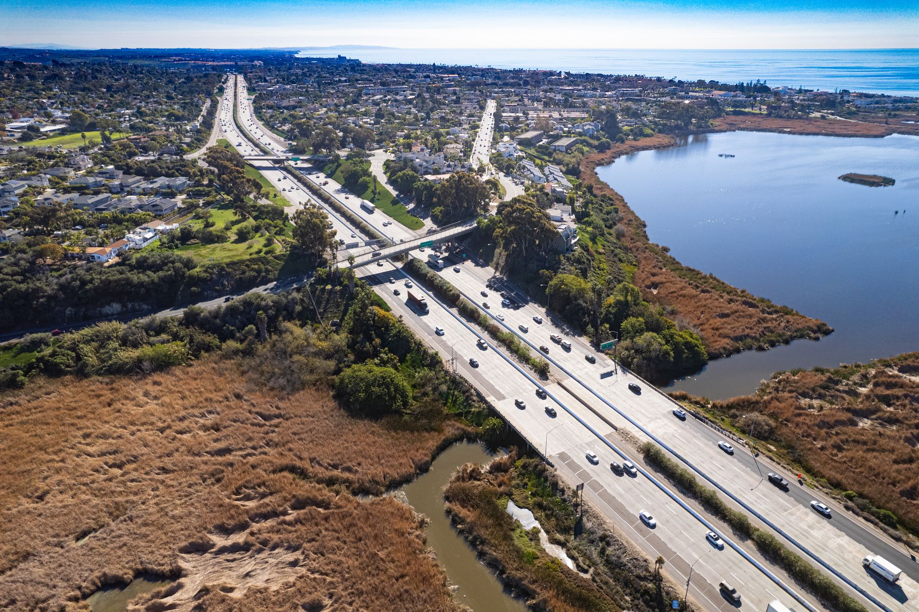 Aerial shot of Carlsbad's scenic highway with adjacent lagoon under a clear blue sky